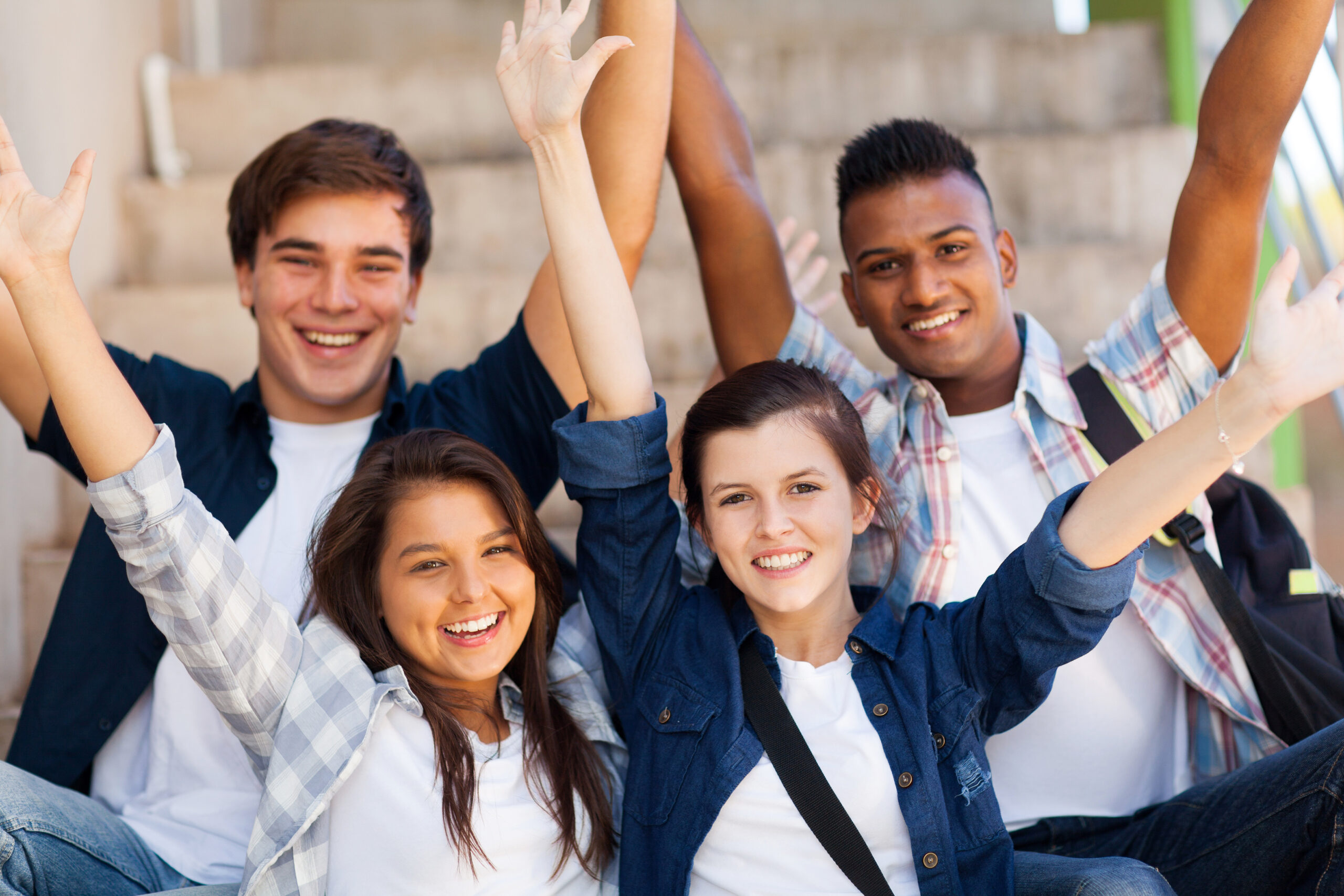 excited high school students with arms outstretched outdoors